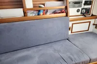 Cozy interior of 2017 Rustler 33 sailboat with blue cushions and wooden shelving.