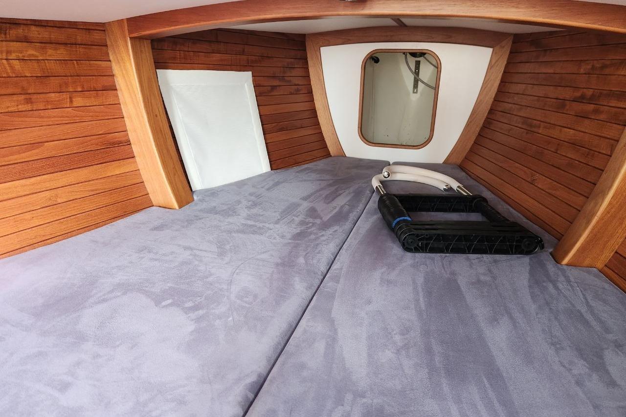 Interior cabin of 2017 Rustler 33 sailboat with wooden paneling and cozy bedding.