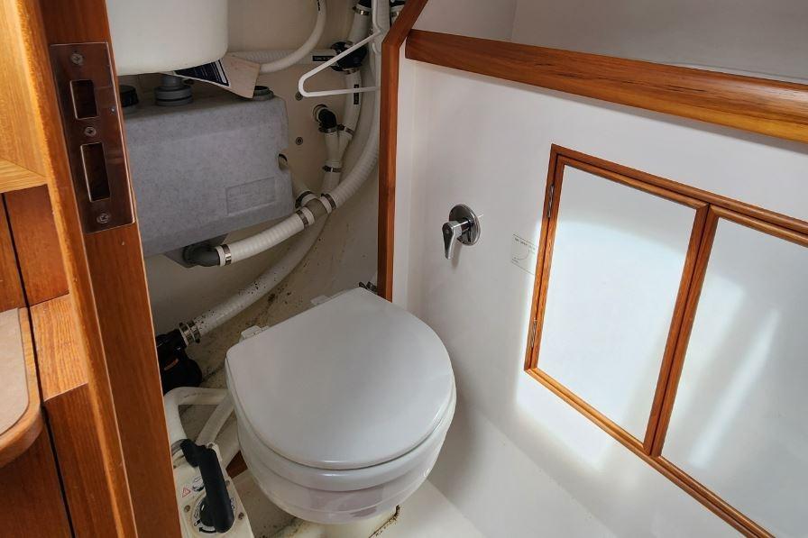 Compact marine bathroom in 2017 Rustler 33 yacht with wooden accents and plumbing.