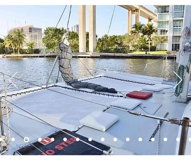  Yacht Photos Pics 1987 Custom Suncoast Catamaran docked by waterfront with lush greenery and modern buildings.