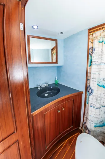 Carolina Girl Yacht Photos Pics 1993 Jarrett Bay Convertible yacht bathroom with wooden cabinetry and nautical-themed shower curtain.