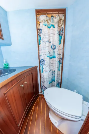 Carolina Girl Yacht Photos Pics 1993 Jarrett Bay Convertible bathroom with nautical-themed shower curtain and wooden cabinetry.