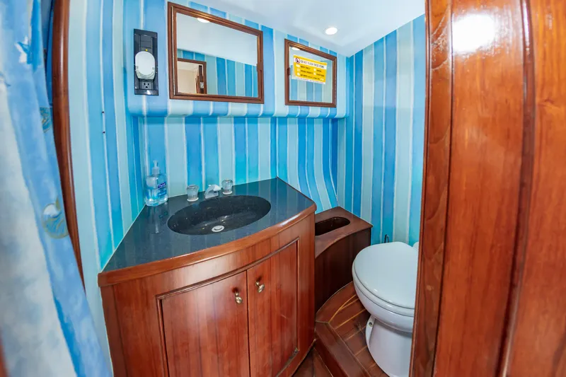 Carolina Girl Yacht Photos Pics 1993 Jarrett Bay Convertible bathroom with blue striped walls, wooden cabinetry, and modern fixtures.