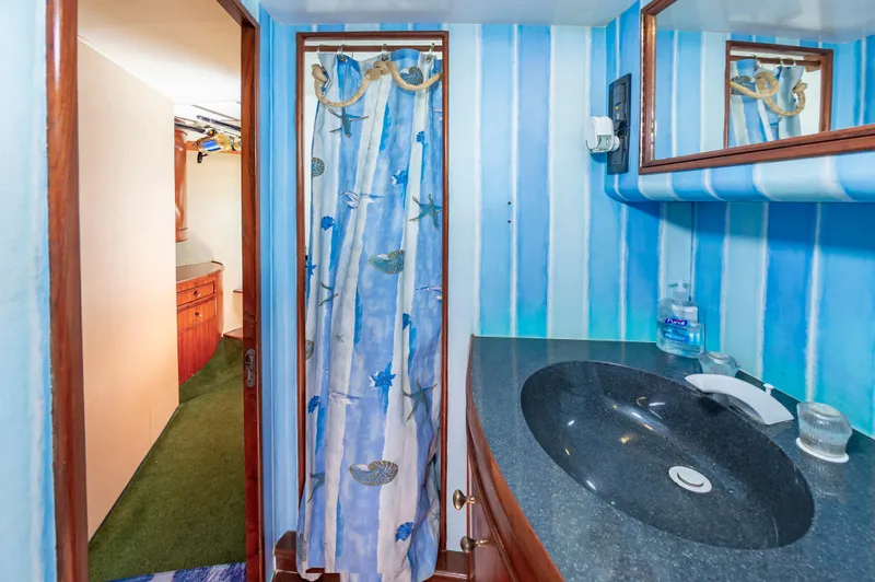 Carolina Girl Yacht Photos Pics Bathroom interior of 1993 Jarrett Bay Convertible yacht with blue striped walls and black countertop.