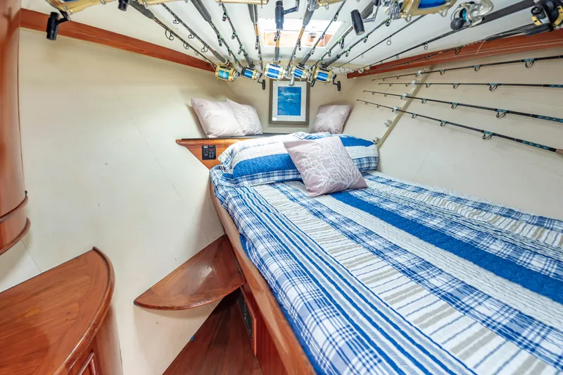 Carolina Girl Yacht Photos Pics Cozy cabin interior of 1993 Jarrett Bay Convertible with fishing rods and striped bedding.