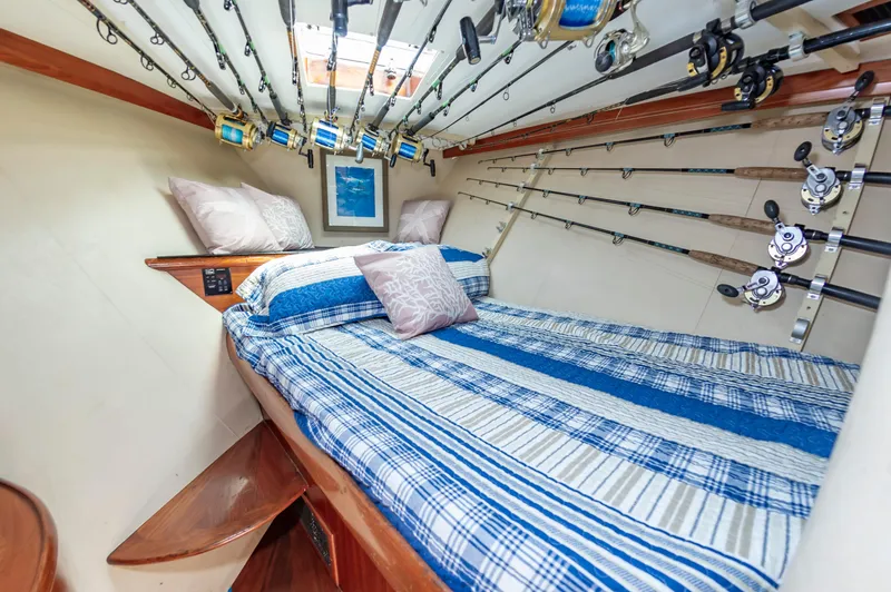 Carolina Girl Yacht Photos Pics Cozy cabin interior of 1993 Jarrett Bay Convertible with fishing rods and striped bedding.