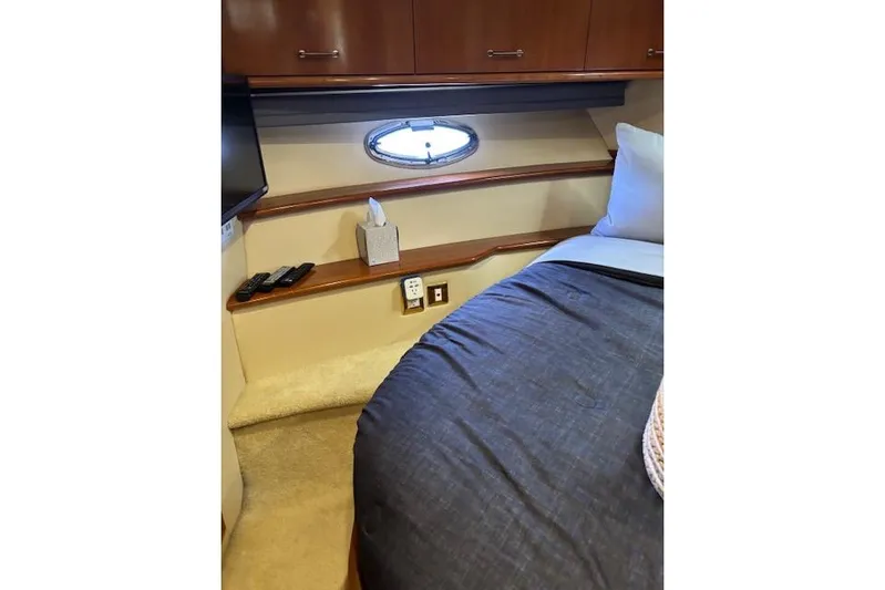  Yacht Photos Pics Interior of 2004 Carver 466 Motor Yacht bedroom with porthole, bed, and storage cabinets.