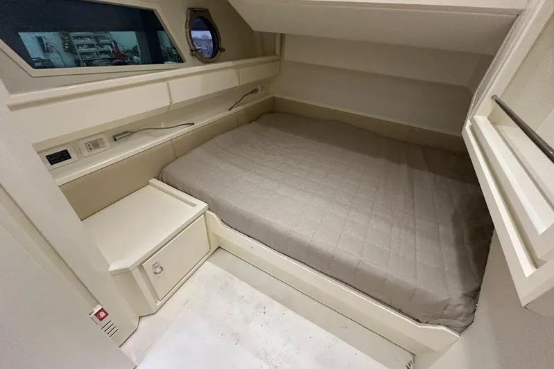  Yacht Photos Pics Cozy cabin interior of 2013 Itama 62 yacht with a comfortable bed and porthole window.
