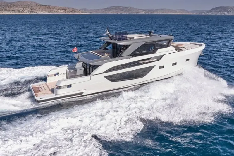  Yacht Photos Pics 2024 Bluegame BGX63 yacht cruising on open sea with scenic coastal backdrop.