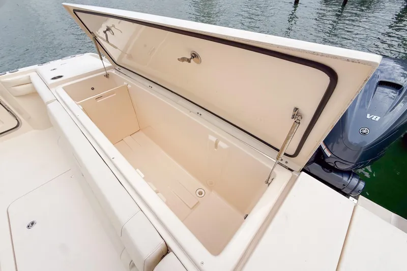  Yacht Photos Pics 2022 Grady-White Canyon 456 boat with open storage compartment, docked by water.
