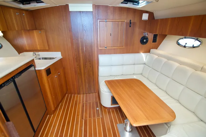 Revelry Yacht Photos Pics 2002 Tiara Yachts 3500 Open interior with wood cabinetry, white seating, and compact kitchen area.