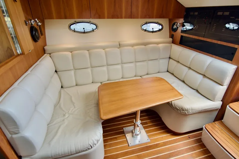 Revelry Yacht Photos Pics Interior of 2002 Tiara Yachts 3500 Open with cushioned seating and wooden table.