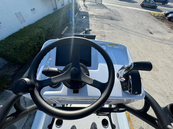  Yacht Photos Pics 2025 Yellowfin 24 CE boat helm with steering wheel and controls, parked outdoors.