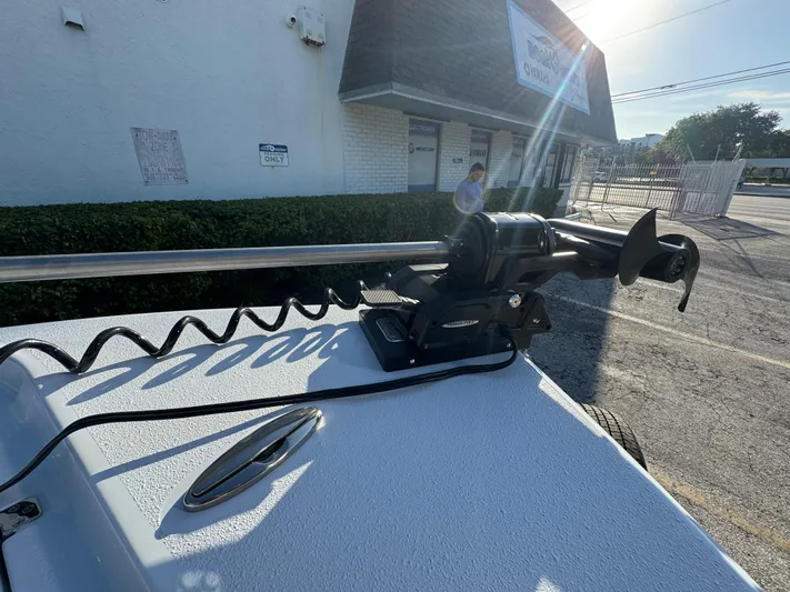  Yacht Photos Pics 2025 Yellowfin 24 CE boat with mounted trolling motor in a sunny outdoor setting.