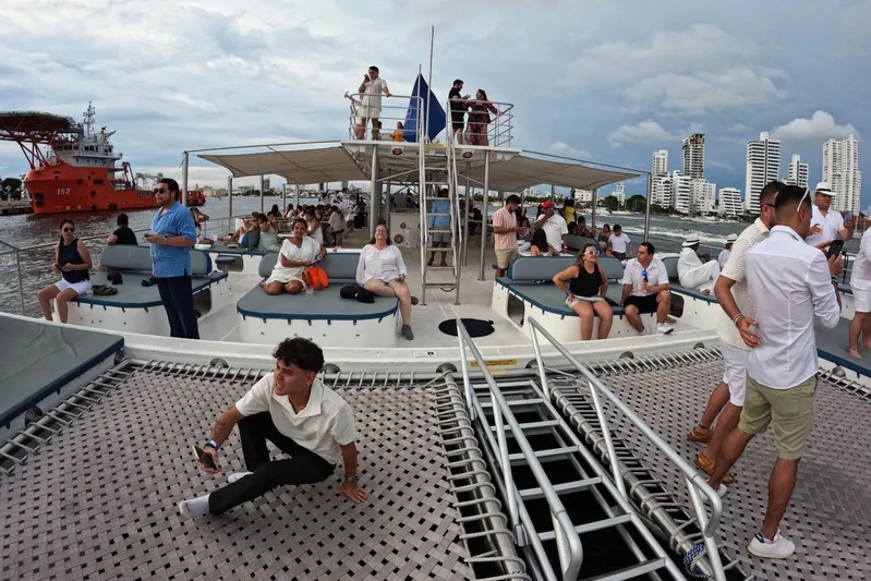  Yacht Photos Pics People relaxing on a Custom PaxCat 80 catamaran, 2024, with city skyline in background.
