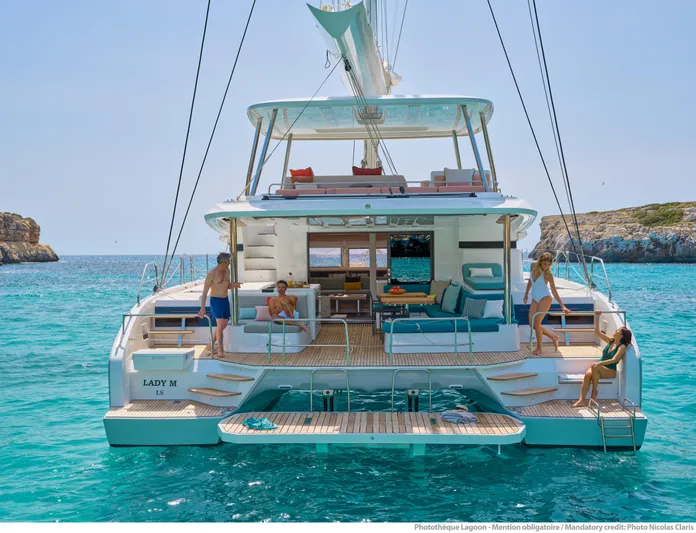  Yacht Photos Pics 2024 Lagoon 55 yacht on turquoise water, featuring spacious deck and lounging area.