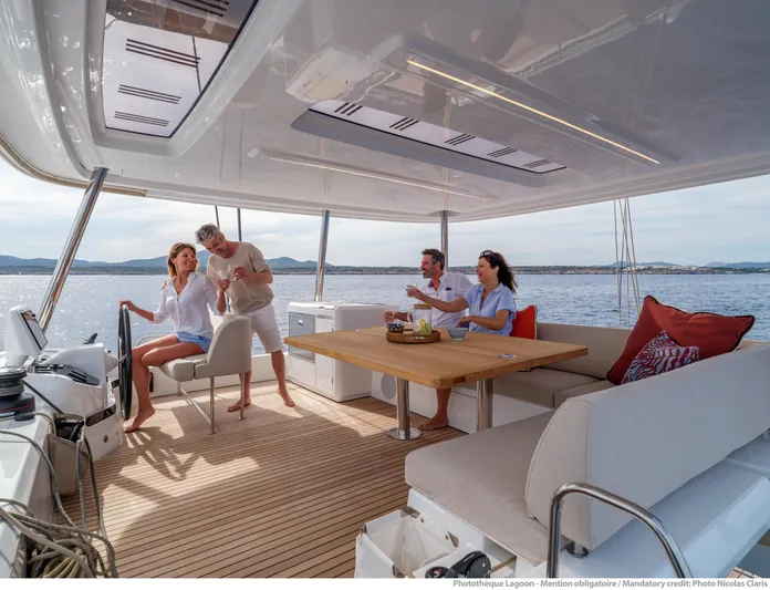  Yacht Photos Pics 2024 Lagoon 55 yacht interior with people enjoying a meal on deck.