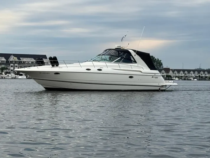  Yacht Photos Pics 2000 Cruisers Yachts 3870 Express on calm water with houses in the background.