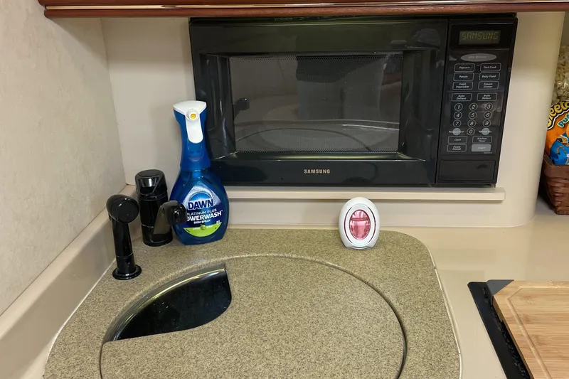 Yacht Photos Pics Kitchen area in 2000 Cruisers Yachts 3870 Express with microwave and cleaning supplies.