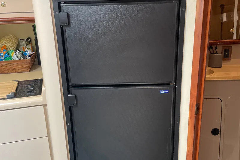  Yacht Photos Pics Black refrigerator in 2000 Cruisers Yachts 3870 Express kitchen, with snacks on the counter.