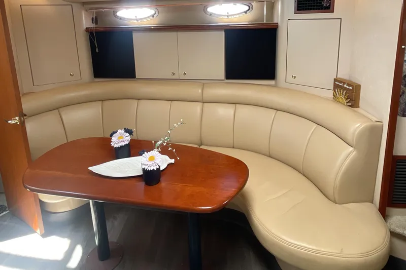  Yacht Photos Pics Luxurious interior of 2000 Cruisers Yachts 3870 Express with curved seating and wooden table.