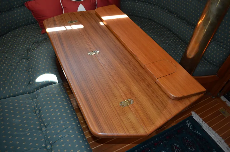 Fleur De Lys Yacht Photos Pics Wooden table in a 1986 Hans Christian Christina yacht interior, surrounded by cushioned seating.