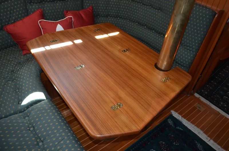 Fleur De Lys Yacht Photos Pics Wooden table in 1986 Hans Christian Christina yacht interior with cushioned seating and brass accents.