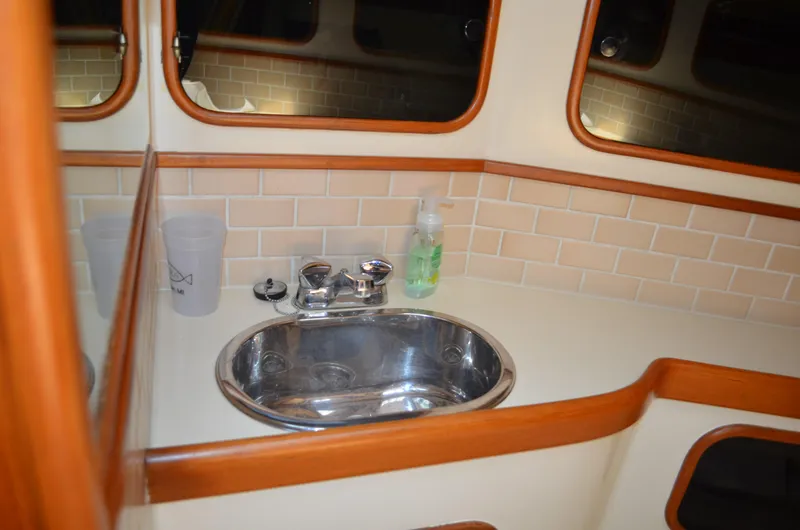 Fleur De Lys Yacht Photos Pics 1986 Hans Christian Christina yacht bathroom with sink, mirror, and tiled backsplash.