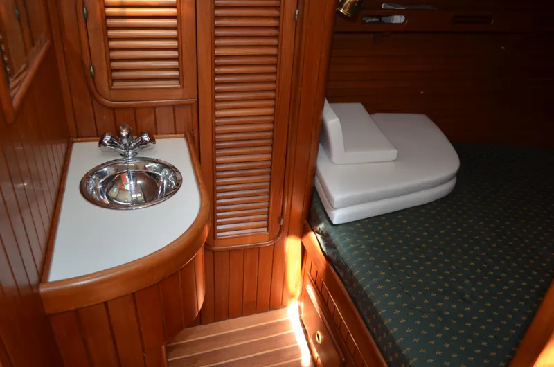Fleur De Lys Yacht Photos Pics 1986 Hans Christian Christina yacht interior with wooden finish, sink, and cushioned seating.