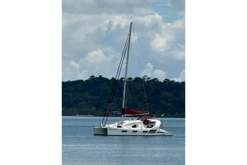 Manila Spirit Yacht Photos Pics Sailing catamaran Dean 5000, 2012 model, anchored on calm waters with lush forest backdrop.