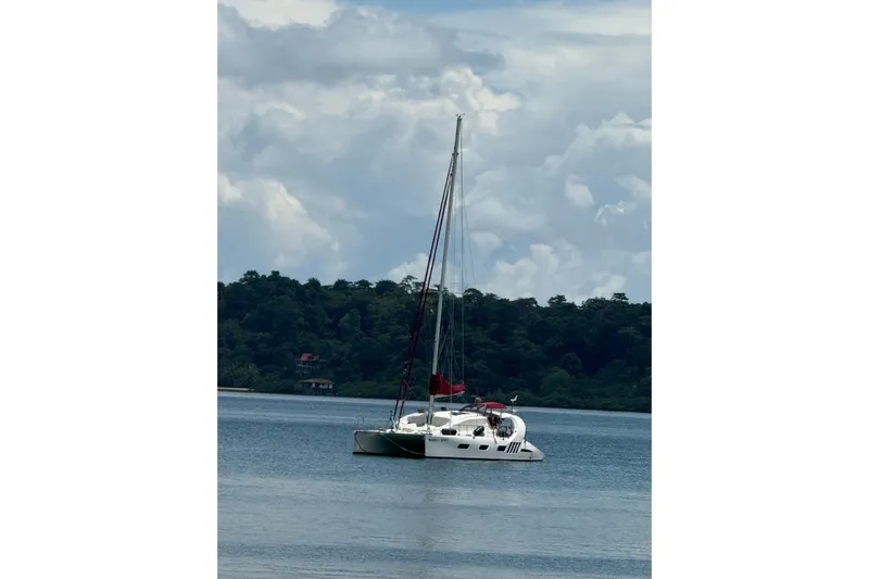 Manila Spirit Yacht Photos Pics Sailboat Dean 5000 (2012) anchored on calm water with lush forest backdrop.