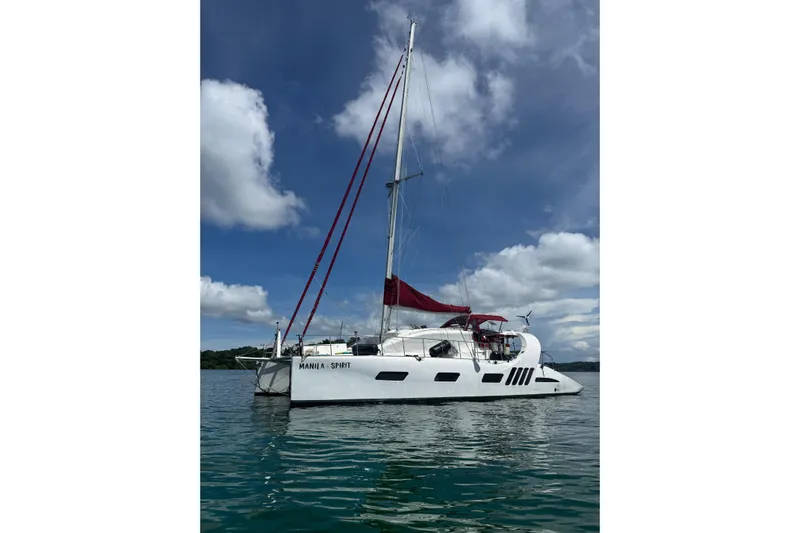 Manila Spirit Yacht Photos Pics 2012 Dean 5000 sailboat with red sails on calm water under blue sky.