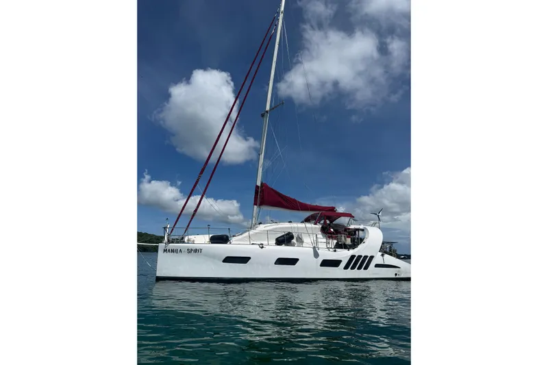 Manila Spirit Yacht Photos Pics Sailing catamaran "Manila Spirit" on water, Dean 5000 model, 2012, with red sails.