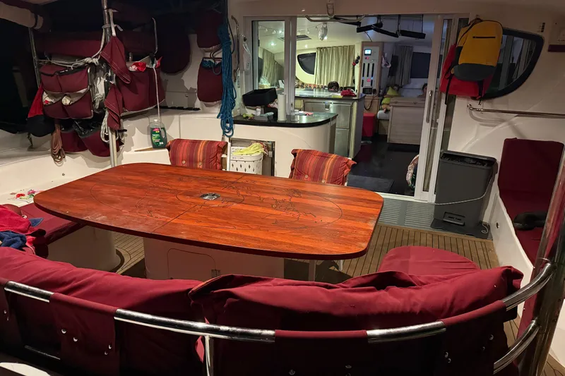Manila Spirit Yacht Photos Pics Interior of a 2012 Dean 5000 yacht with a wooden dining table and red seating.