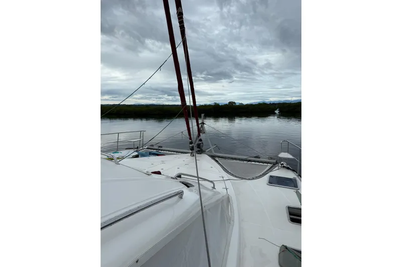 Manila Spirit Yacht Photos Pics Sailing on a 2012 Dean 5000 catamaran under cloudy skies on a calm river.