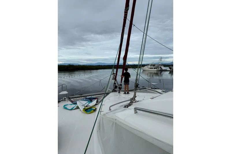 Manila Spirit Yacht Photos Pics Person on deck of 2012 Dean 5000 catamaran, overlooking calm waters and distant boats.