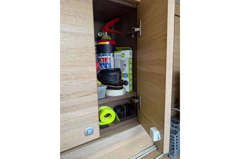 Manila Spirit Yacht Photos Pics Open wooden cabinet with various tools and supplies, including a fire extinguisher and tape.