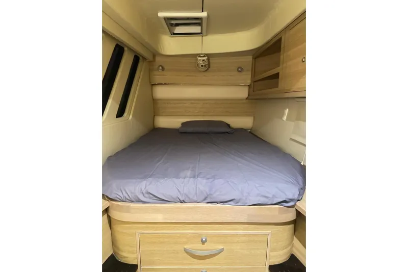 Manila Spirit Yacht Photos Pics Cozy interior of a 2012 Dean 5000 with a neatly made bed and wooden storage.