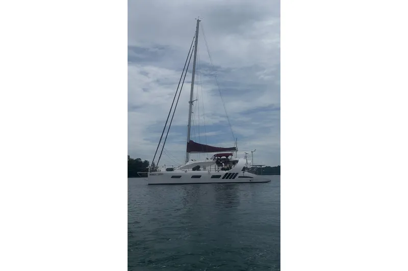 Manila Spirit Yacht Photos Pics Sailing yacht on water, Dean 5000 model, 2012, with maroon sail and cloudy sky.