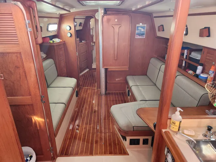 Tilikum III Yacht Photos Pics Interior of 1997 Island Packet 40 sailboat with wooden finishes and cushioned seating.