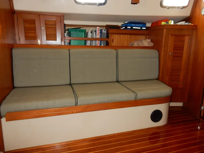 Tilikum III Yacht Photos Pics Interior of 1997 Island Packet 40 sailboat with cushioned seating and wooden cabinetry.