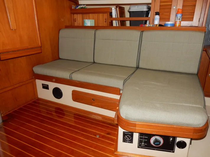 Tilikum III Yacht Photos Pics Interior of 1997 Island Packet 40 sailboat with cushioned seating and wooden flooring.