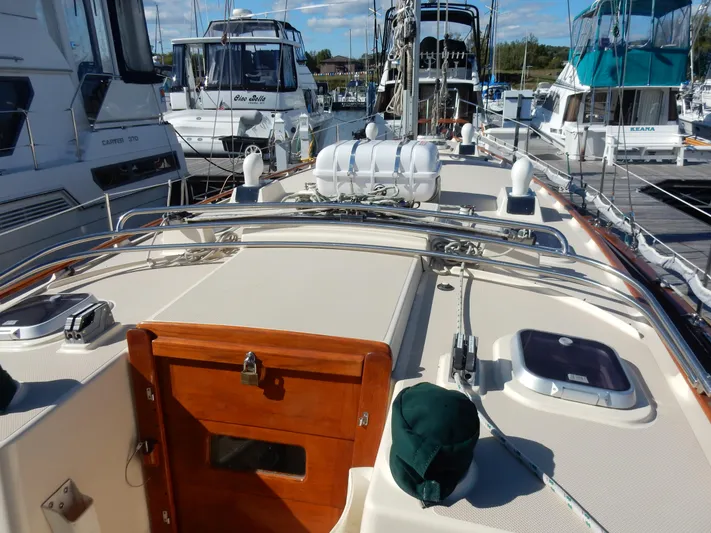 Tilikum III Yacht Photos Pics 1997 Island Packet 40 sailboat deck with wooden hatch, docked among other boats.