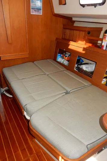 Tilikum III Yacht Photos Pics 1997 Island Packet 40 interior with a cozy, convertible bed and wooden accents.