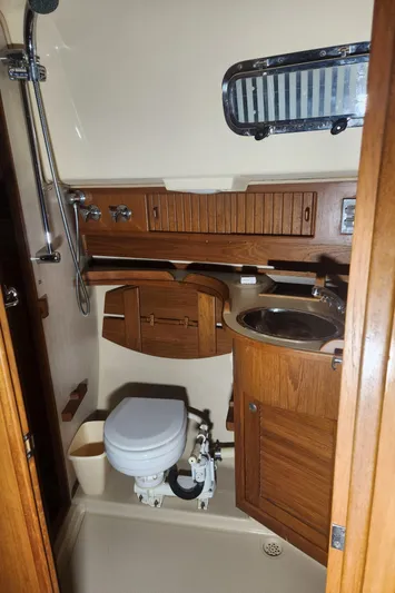 Tilikum III Yacht Photos Pics 1997 Island Packet 40 yacht bathroom with wooden cabinetry and compact fixtures.