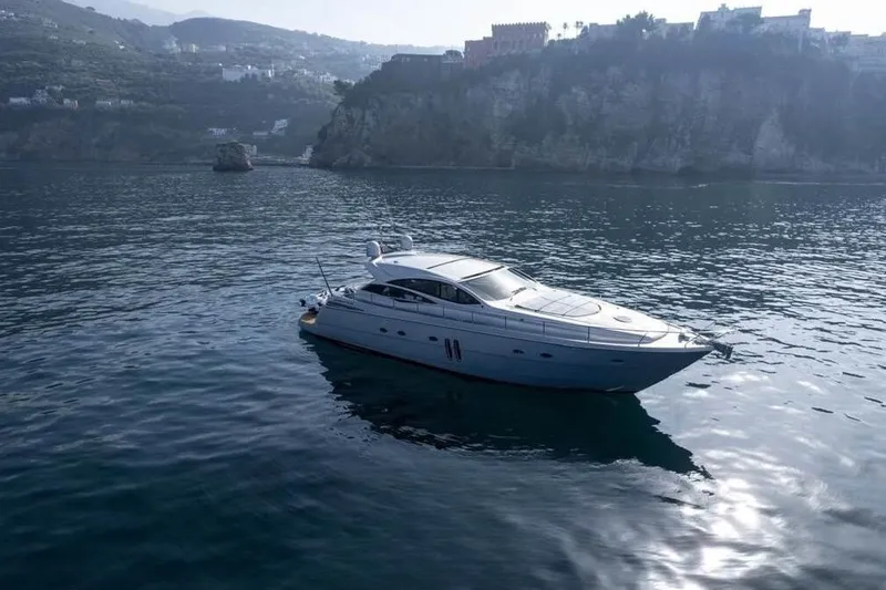  Yacht Photos Pics Luxury 2005 Pershing 62 yacht cruising on serene waters near rocky coastline.