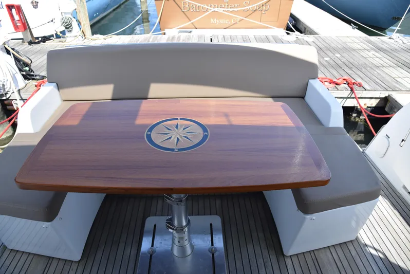 "freedom" Yacht Photos Pics Jeanneau NC 14 2016 boat deck with wooden table and cushioned seating.