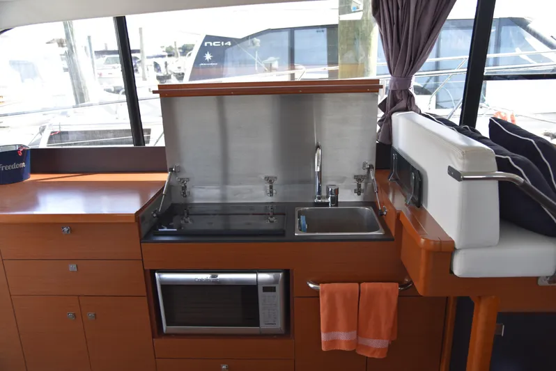 "freedom" Yacht Photos Pics 2016 Jeanneau NC 14 yacht interior kitchen with sink, microwave, and storage cabinets.