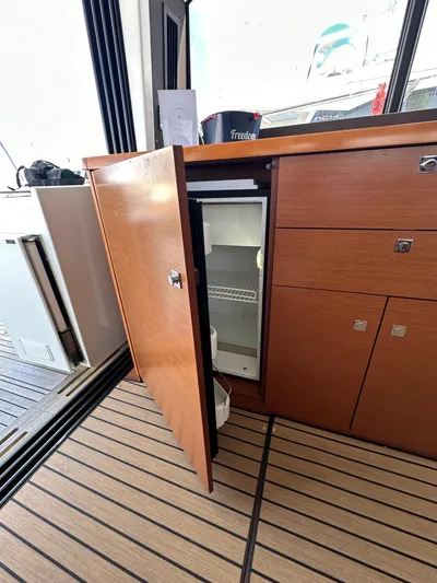 "freedom" Yacht Photos Pics 2016 Jeanneau NC 14 interior with open wooden cabinet and mini fridge.