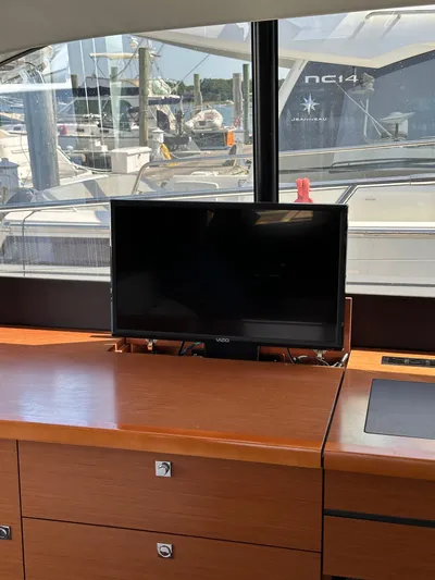 "freedom" Yacht Photos Pics Interior of 2016 Jeanneau NC 14 yacht with TV and wooden cabinetry.